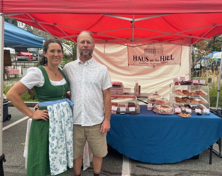 2 people in traditional Austrian attire at a farmers market